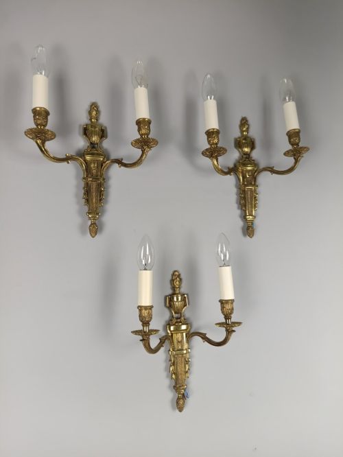 fig 1. Set of three French Louis XVI style twin-arm wall lights in gilded metal with urn backplates and fluted shafts.