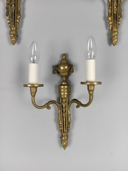 fig 2. A set of three French Neoclassical gilt brass twin-arm wall sconces featuring urn finials and decorative candle branches.