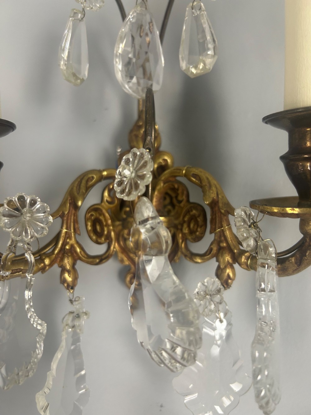 A pair of French gilt brass twin-arm wall lights decorated with scrollwork and hanging crystal drops. View VI