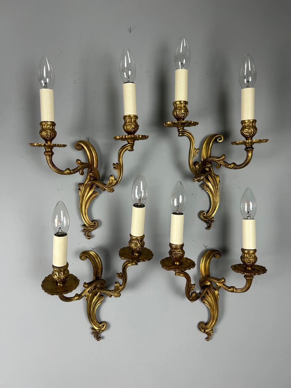 A set of four antique French twin-arm wall lights with a gilded finish and candle-style bulbs. View II