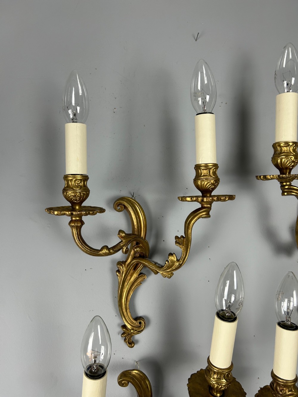 A set of four antique French twin-arm wall lights with a gilded finish and candle-style bulbs. View IV