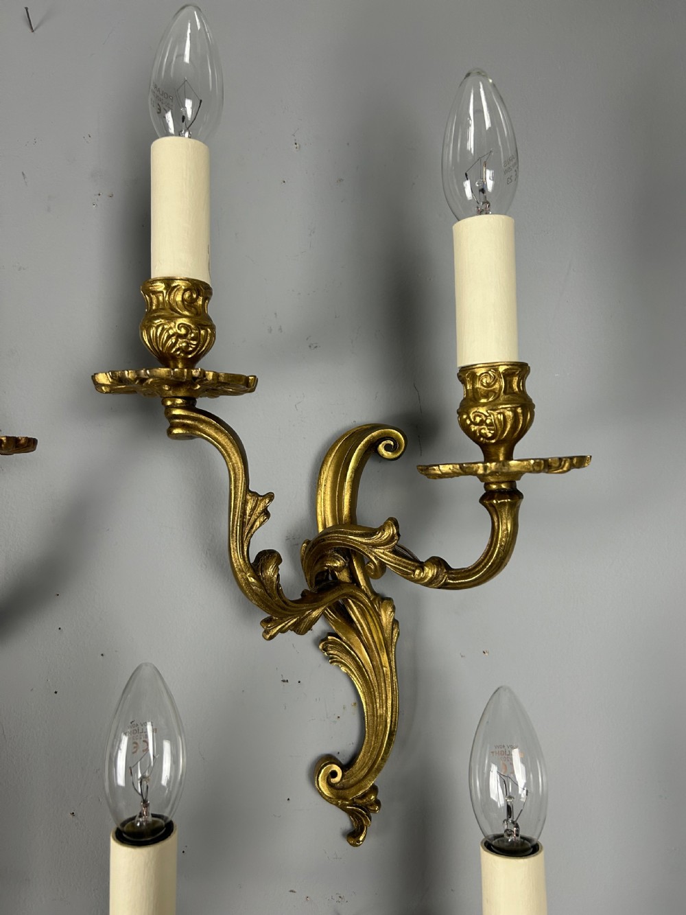 A set of four antique French twin-arm wall lights with a gilded finish and candle-style bulbs. View IX