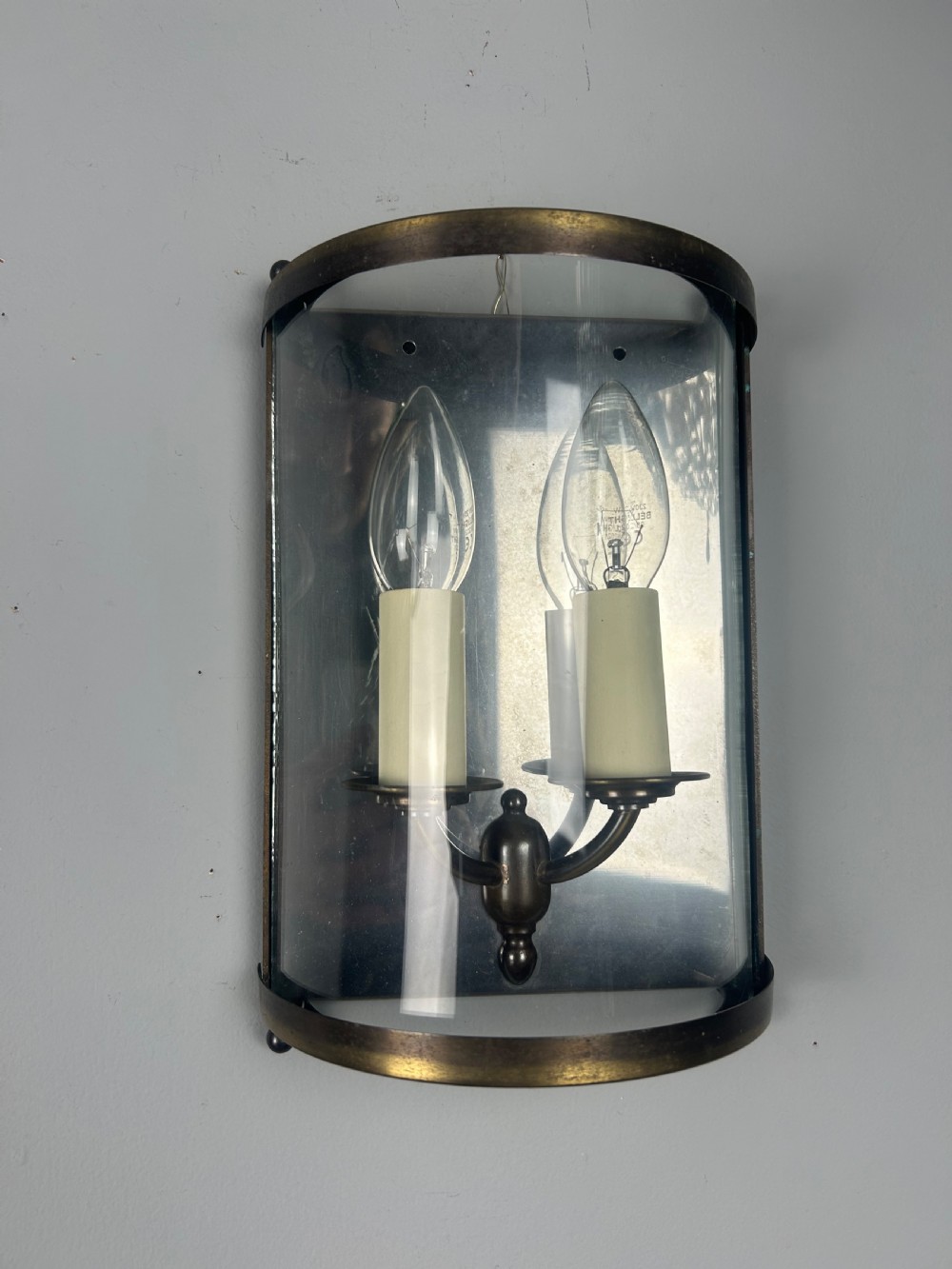 A half-cylinder brass wall light featuring curved glass panels and two candle-style bulbs. View III