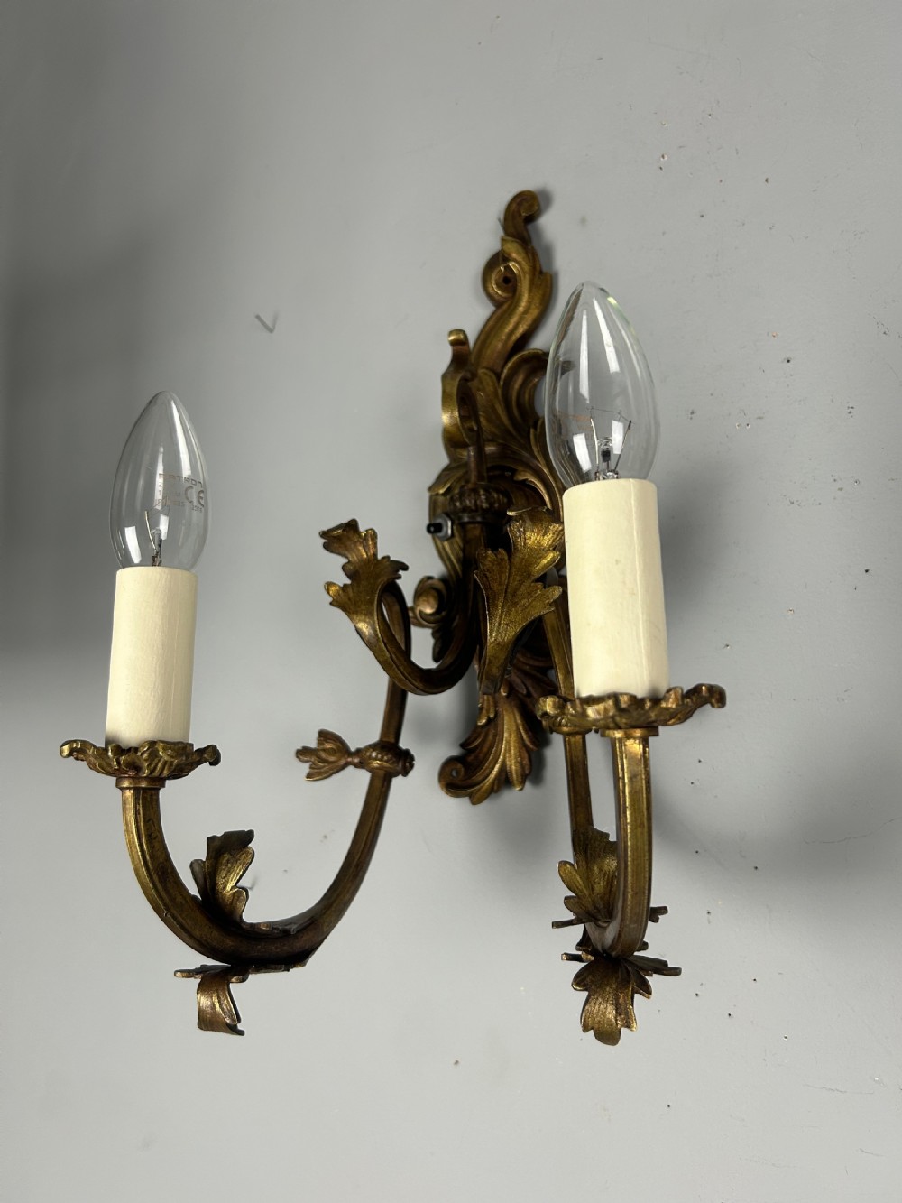 A pair of nineteenth-century French gilt bronze two-arm wall sconces featuring ornate acanthus leaf scrollwork and faux-candle sleeves. View II