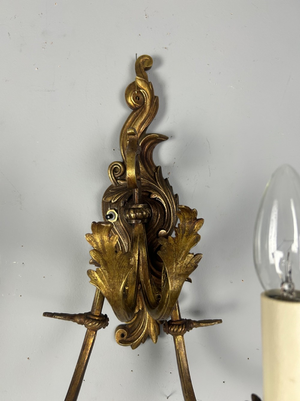 A pair of nineteenth-century French gilt bronze two-arm wall sconces featuring ornate acanthus leaf scrollwork and faux-candle sleeves. View IV