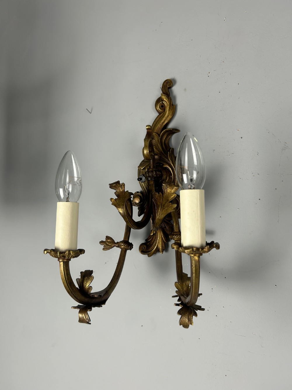 A pair of nineteenth-century French gilt bronze two-arm wall sconces featuring ornate acanthus leaf scrollwork and faux-candle sleeves. View VI