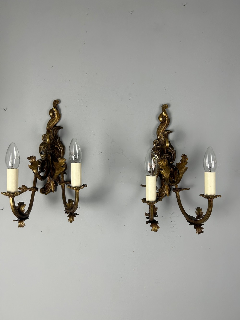 A pair of nineteenth-century French gilt bronze two-arm wall sconces featuring ornate acanthus leaf scrollwork and faux-candle sleeves. View VIII