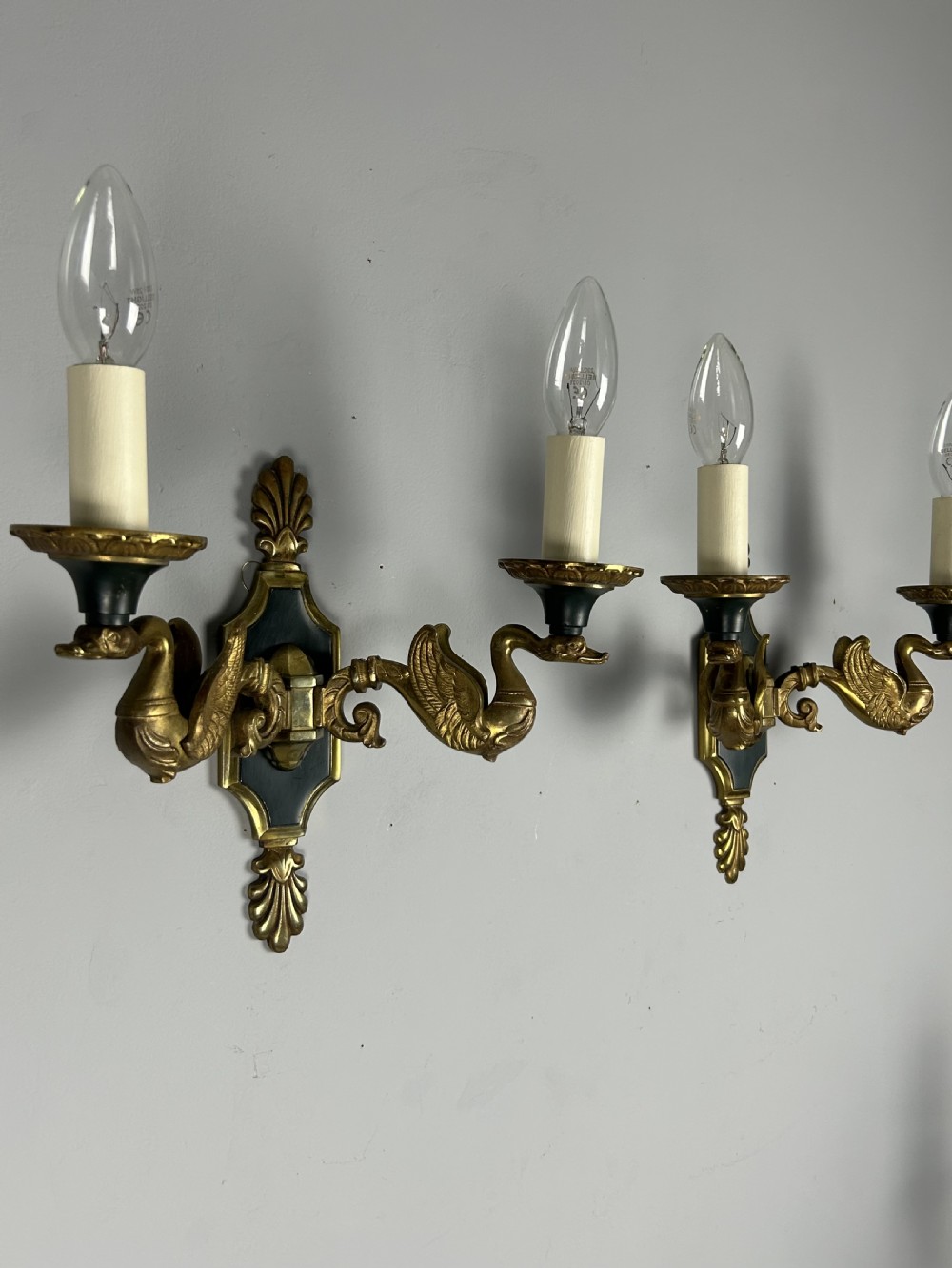 A pair of French Empire style double-arm gilt brass wall sconces featuring sculpted swan-neck branches and central palmette backplates. View II