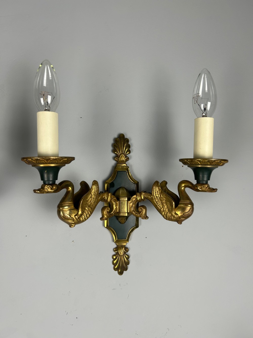 A pair of French Empire style double-arm gilt brass wall sconces featuring sculpted swan-neck branches and central palmette backplates. View III