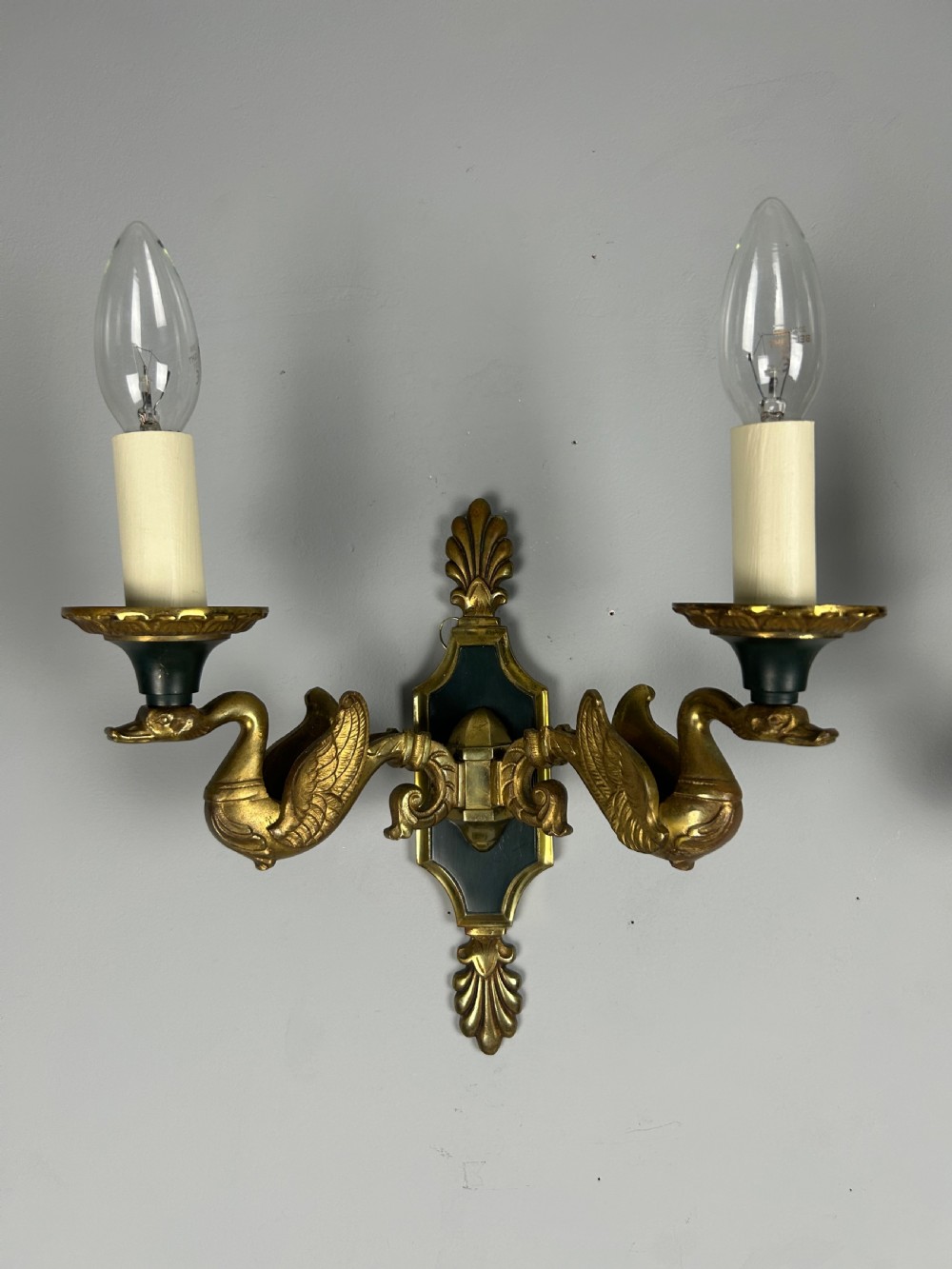 A pair of French Empire style double-arm gilt brass wall sconces featuring sculpted swan-neck branches and central palmette backplates. View IV