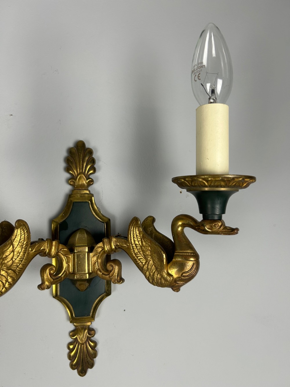 A pair of French Empire style double-arm gilt brass wall sconces featuring sculpted swan-neck branches and central palmette backplates. View VI