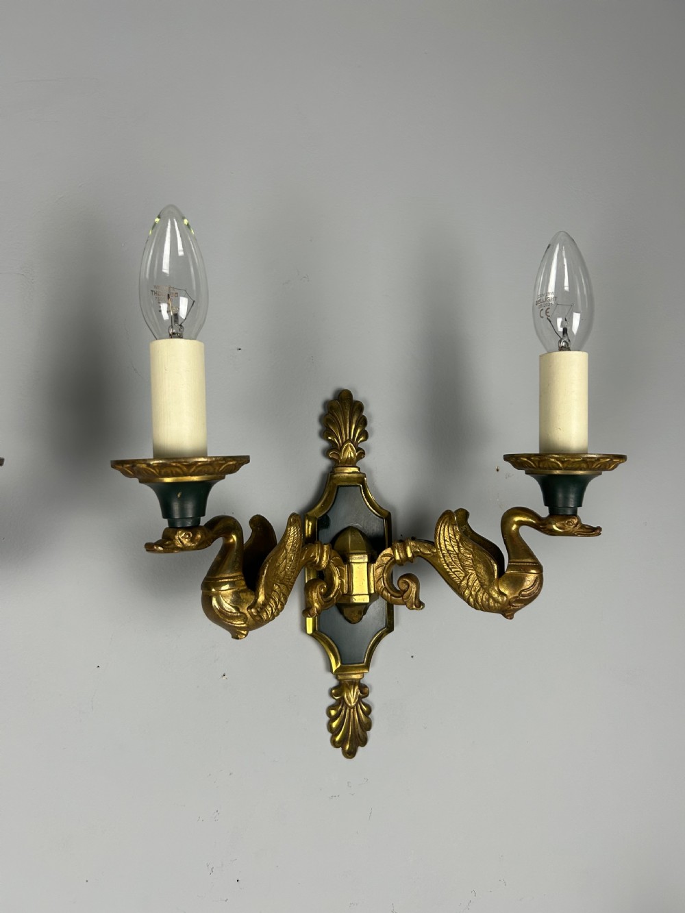 A pair of French Empire style double-arm gilt brass wall sconces featuring sculpted swan-neck branches and central palmette backplates. View VII