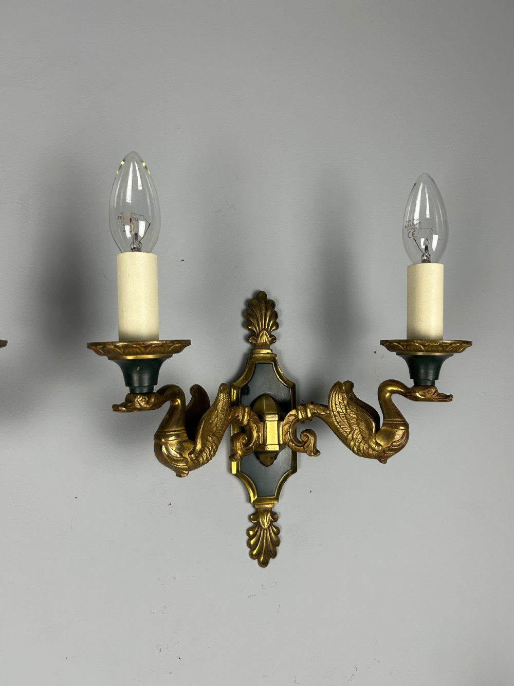 A pair of French Empire style double-arm gilt brass wall sconces featuring sculpted swan-neck branches and central palmette backplates. View VIII