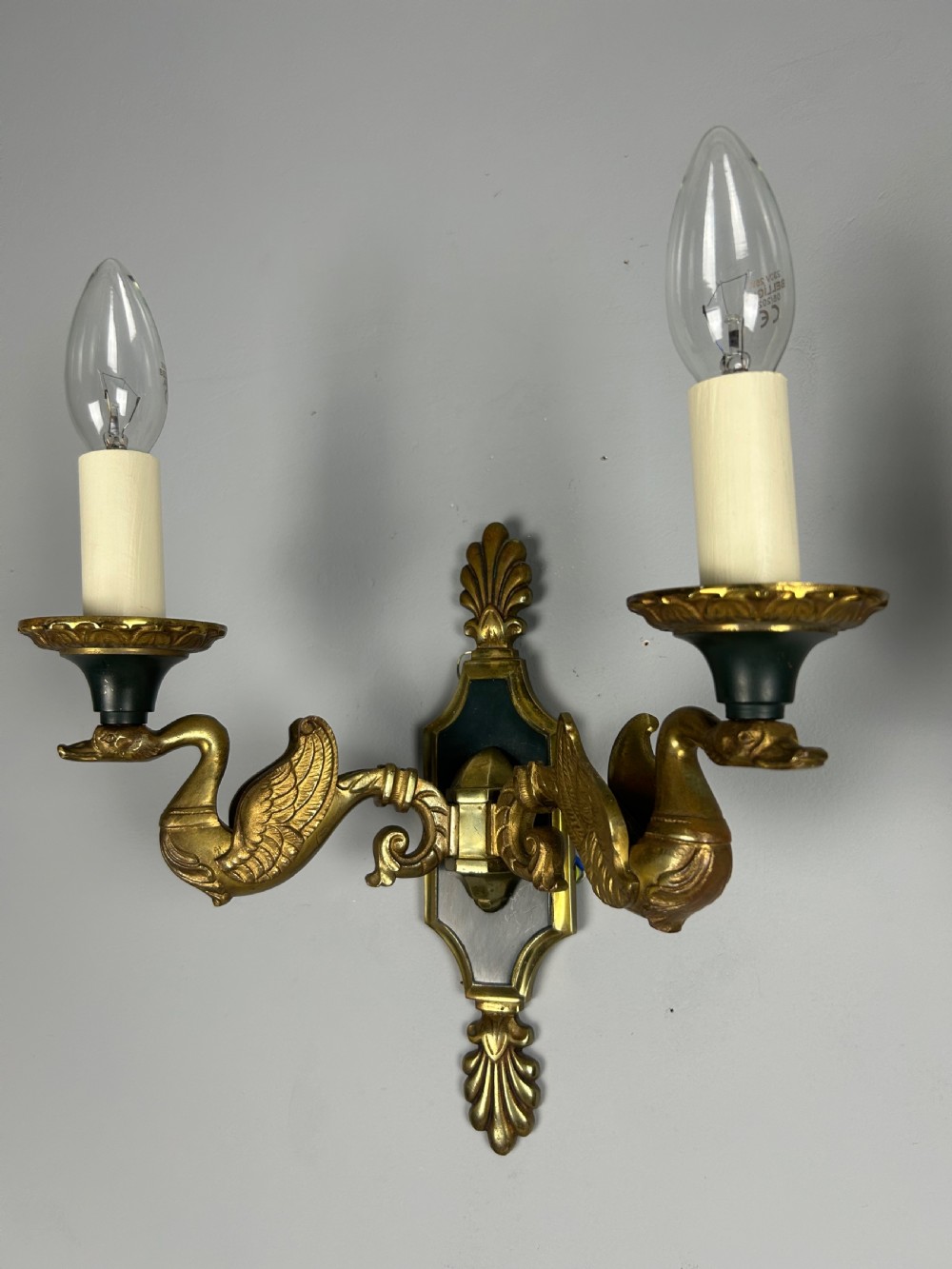 A pair of French Empire style double-arm gilt brass wall sconces featuring sculpted swan-neck branches and central palmette backplates. View IX