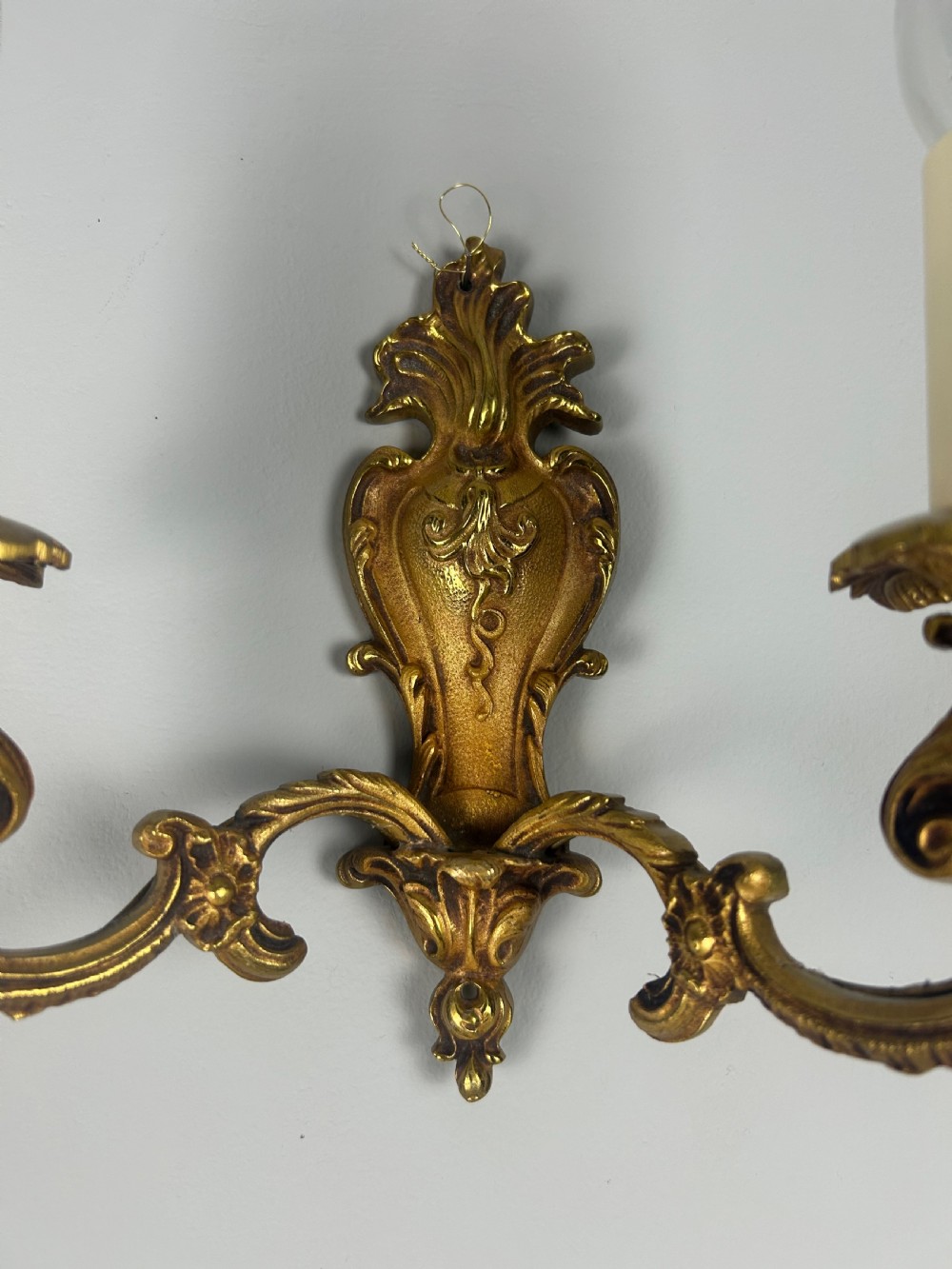 A set of three French Rococo style gilded brass wall lights with twin scroll arms and candle-shaped bulb holders. View V