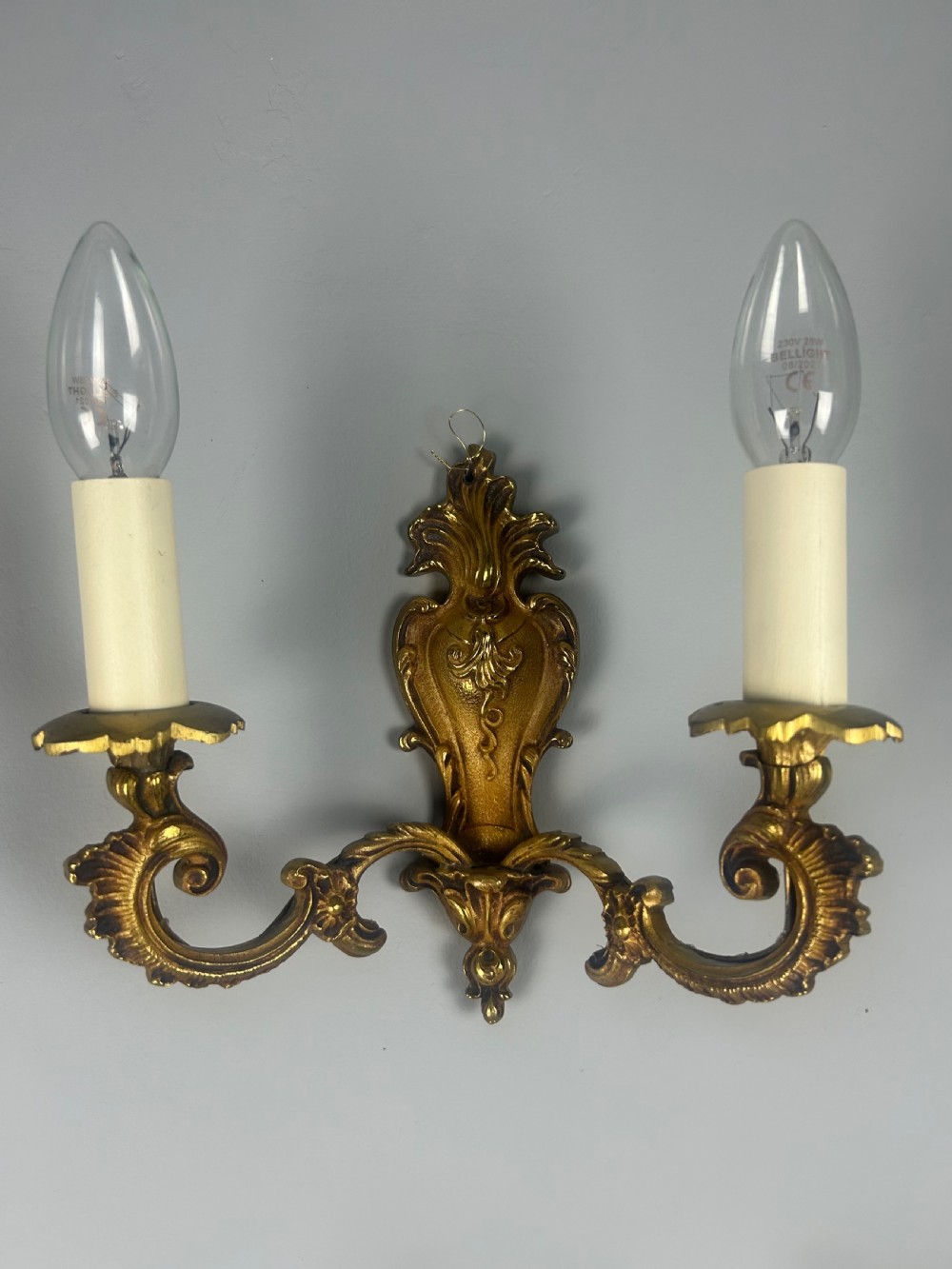 A set of three French Rococo style gilded brass wall lights with twin scroll arms and candle-shaped bulb holders. View IX