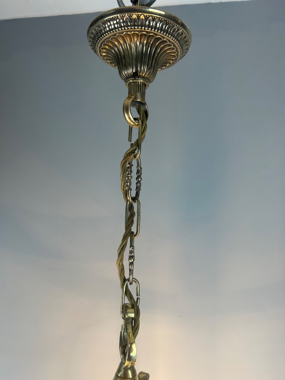 A polished brass cylindrical pendant lantern with clear curved glass panels housing a three-light candle cluster inside. View IV