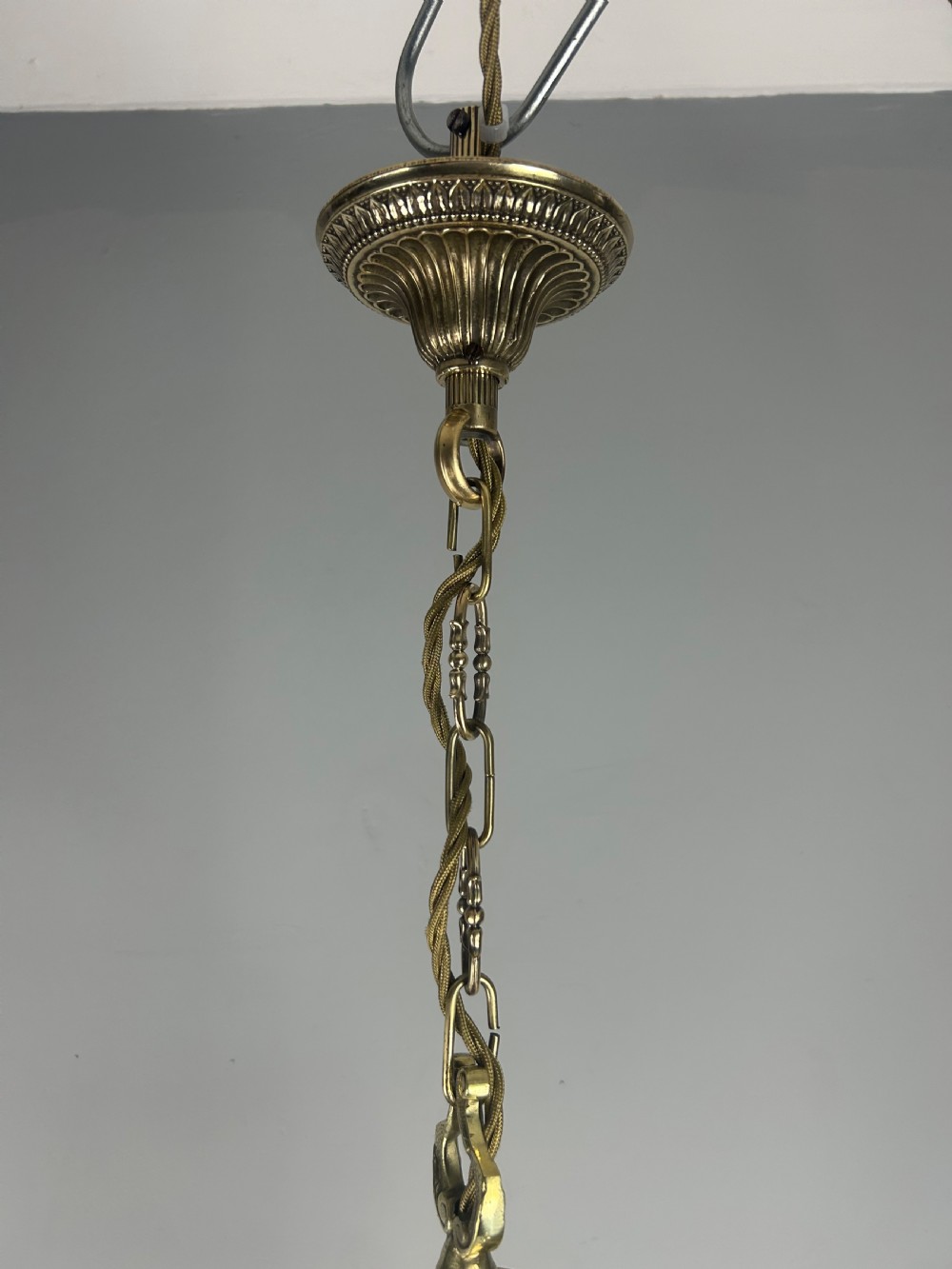 A polished brass cylindrical pendant lantern with clear curved glass panels housing a three-light candle cluster inside. View XII