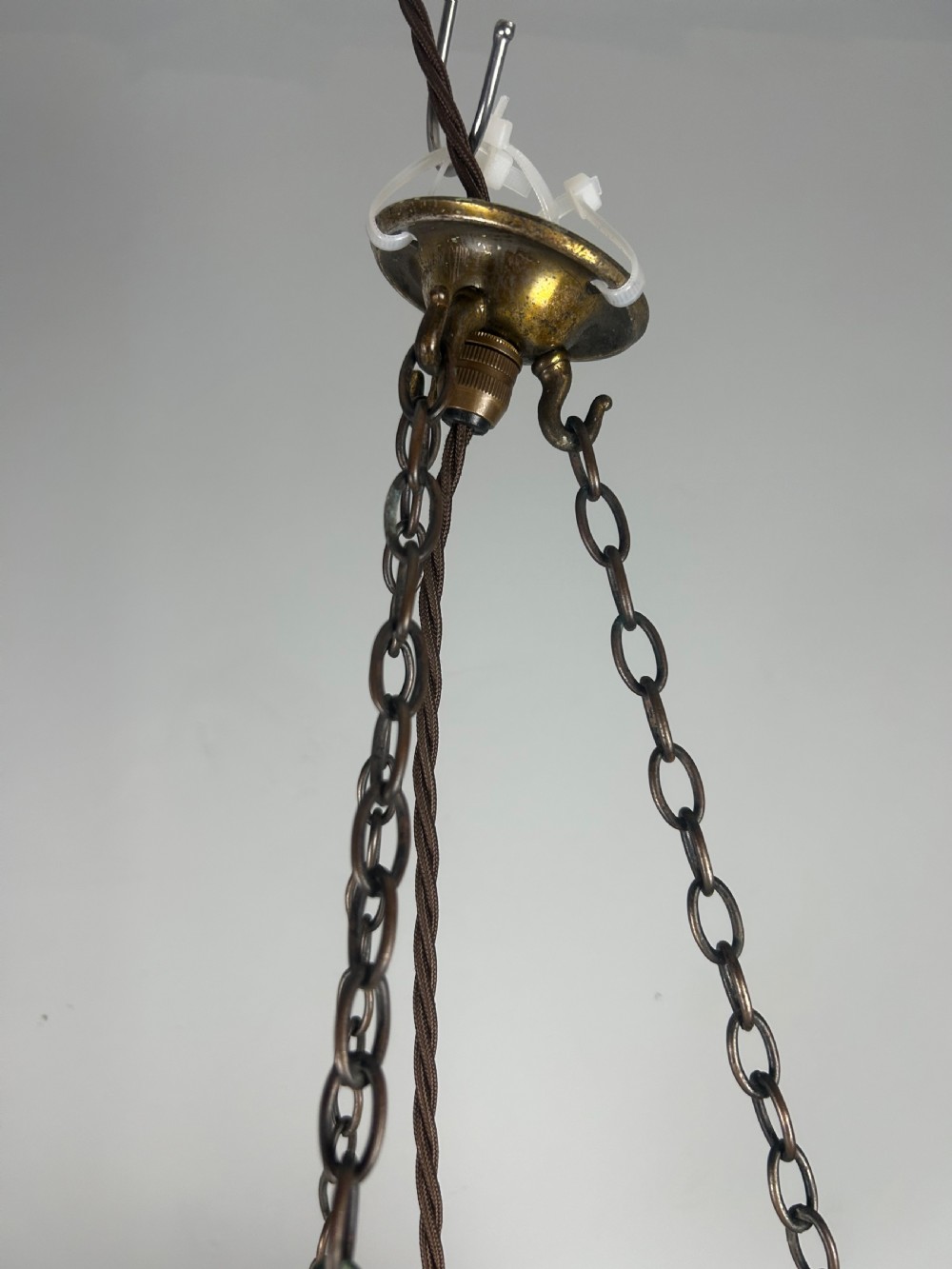 An Art Deco frosted glass plafonnier ceiling light shade with painted blue and orange geometric patterns suspended by brass chains. View III