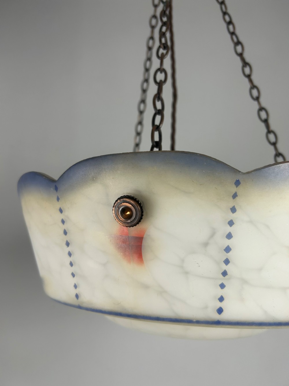 An Art Deco frosted glass plafonnier ceiling light shade with painted blue and orange geometric patterns suspended by brass chains. View VI