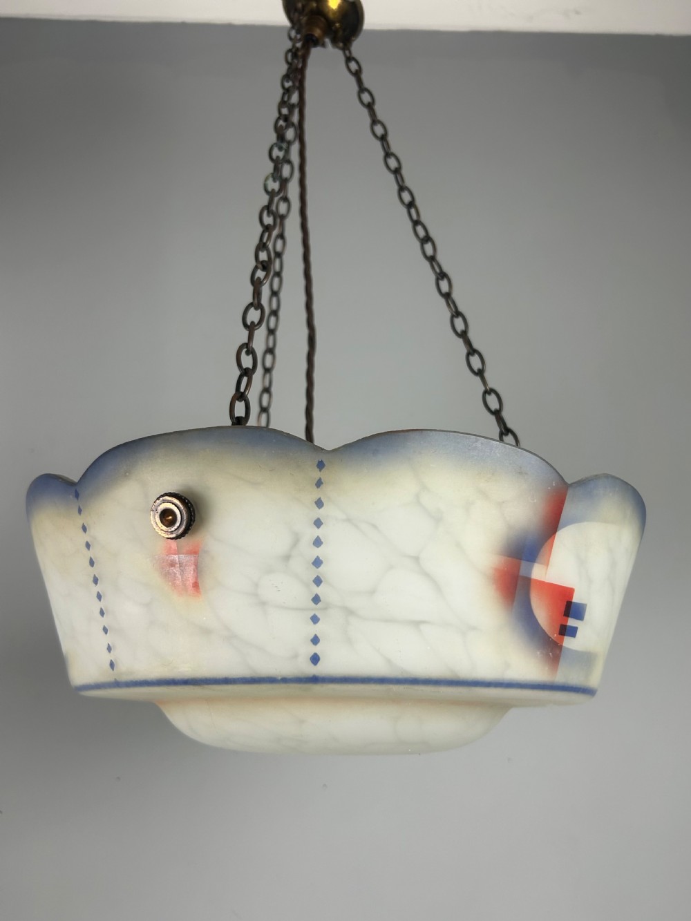 An Art Deco frosted glass plafonnier ceiling light shade with painted blue and orange geometric patterns suspended by brass chains. View VII