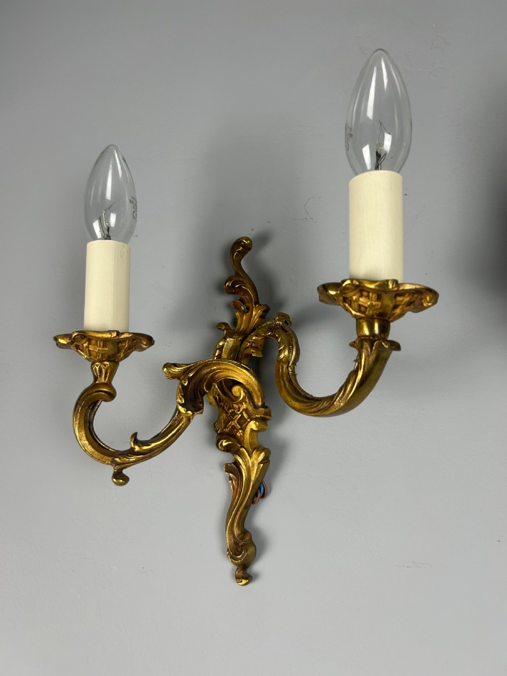 A pair of French Rococo style gilded bronze two-light wall sconces featuring acanthus leaf scrolls and candle-effect sleeves. View VI
