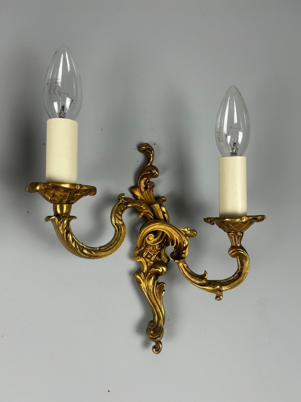 A pair of French Rococo style gilded bronze two-light wall sconces featuring acanthus leaf scrolls and candle-effect sleeves. View VIII
