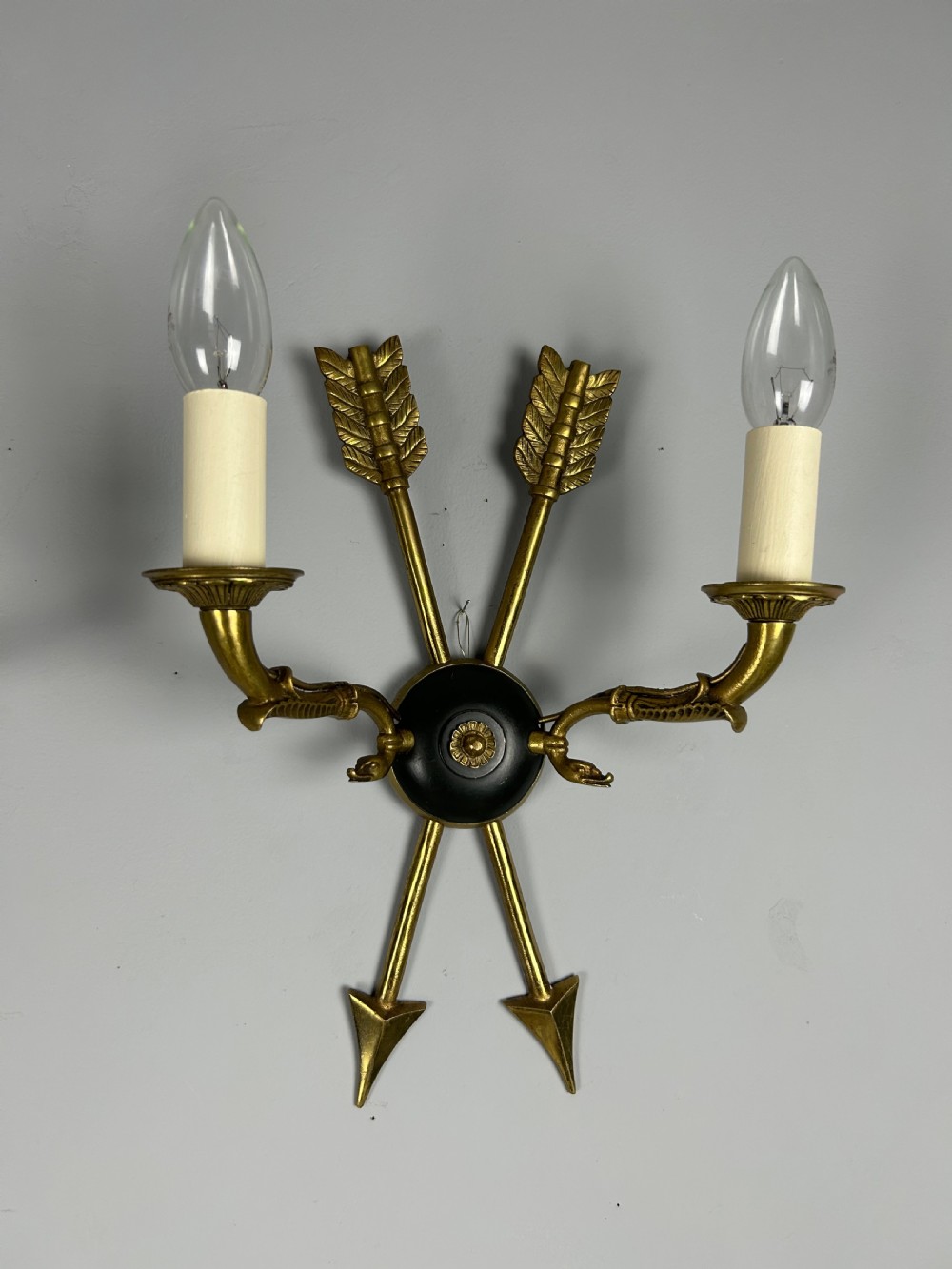 A pair of French Empire style brass and black metal wall sconces featuring crossed arrow backplates and swan neck candle arms. View III