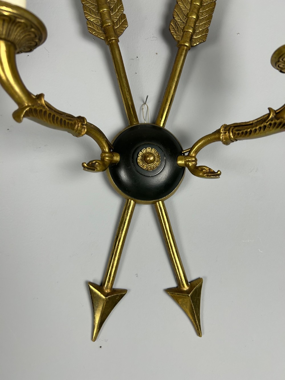 A pair of French Empire style brass and black metal wall sconces featuring crossed arrow backplates and swan neck candle arms. View IV