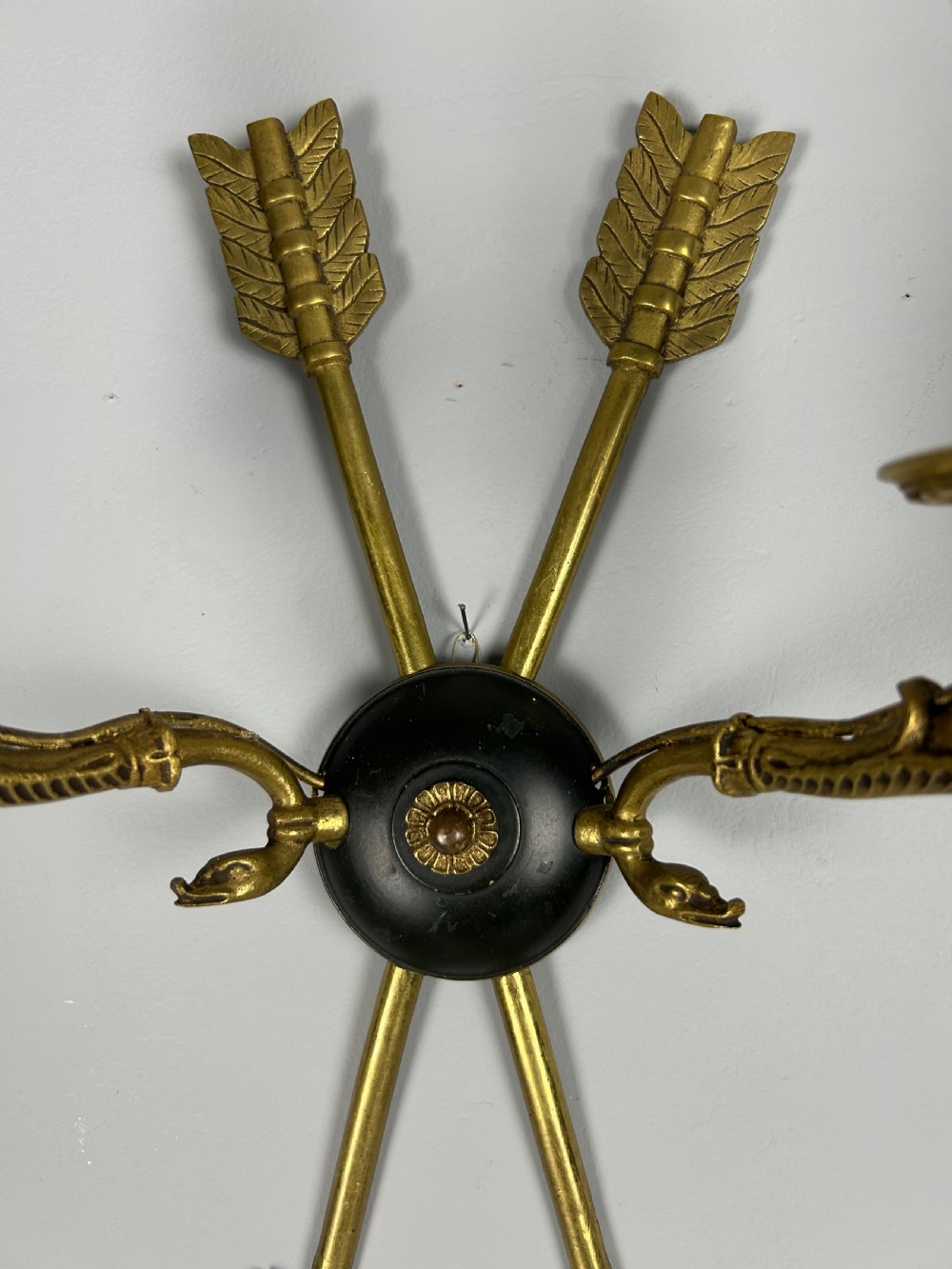 A pair of French Empire style brass and black metal wall sconces featuring crossed arrow backplates and swan neck candle arms. View VI