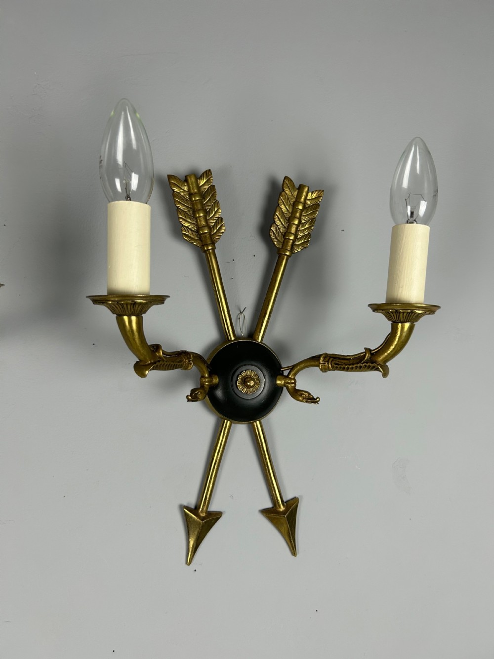 A pair of French Empire style brass and black metal wall sconces featuring crossed arrow backplates and swan neck candle arms. View VIII