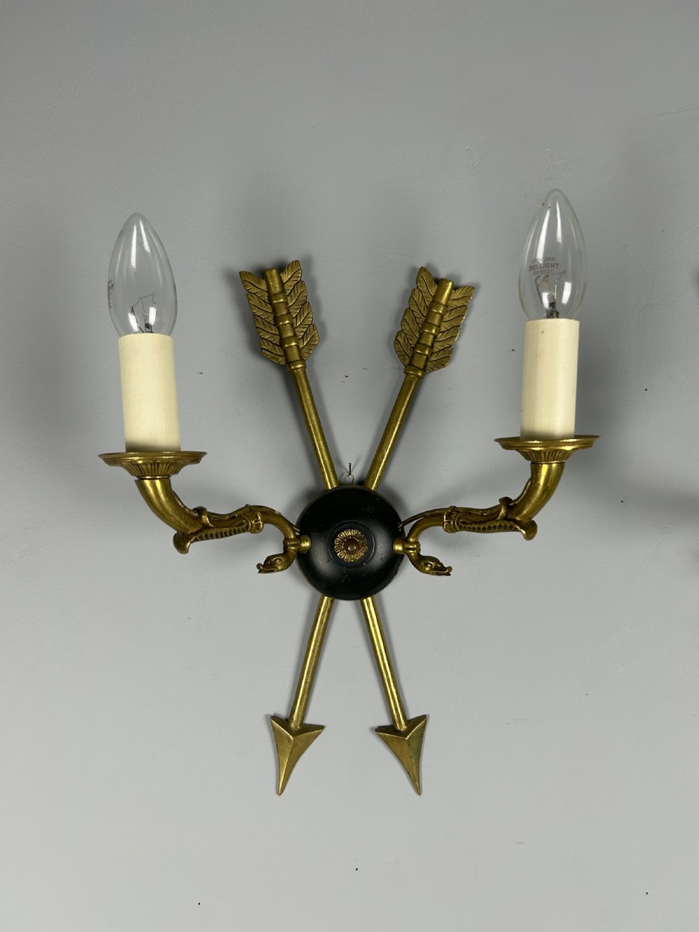 A pair of French Empire style brass and black metal wall sconces featuring crossed arrow backplates and swan neck candle arms. View IX