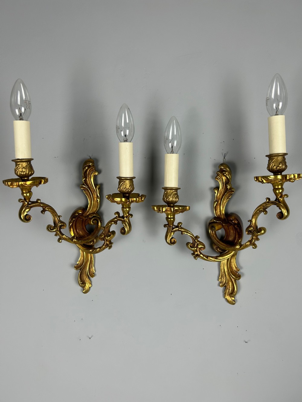 A pair of French Rococo style gilded bronze two-arm wall sconces decorated with ornate acanthus leaf scrollwork. View II