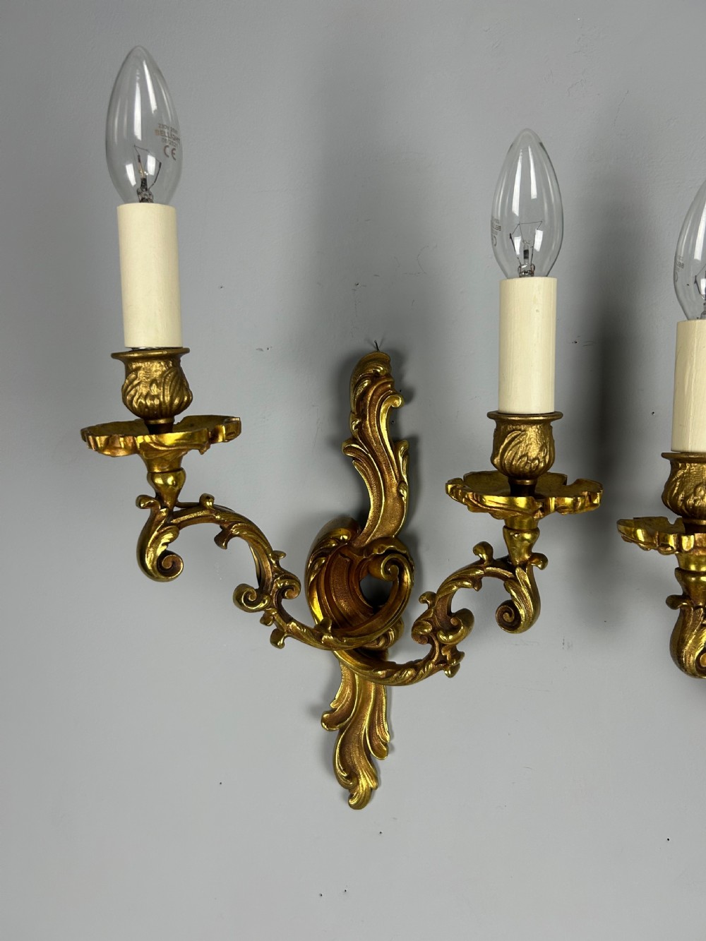 A pair of French Rococo style gilded bronze two-arm wall sconces decorated with ornate acanthus leaf scrollwork. View III