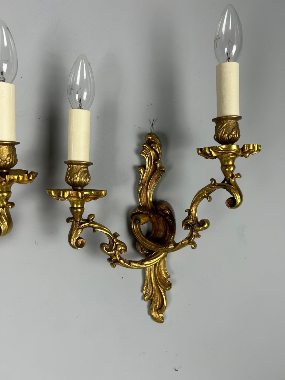 A pair of French Rococo style gilded bronze two-arm wall sconces decorated with ornate acanthus leaf scrollwork. View IV