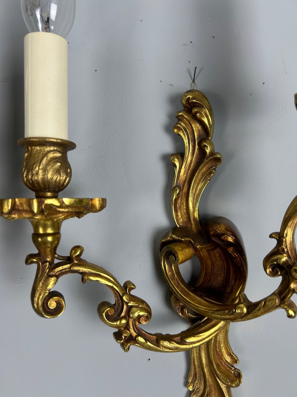 A pair of French Rococo style gilded bronze two-arm wall sconces decorated with ornate acanthus leaf scrollwork. View V