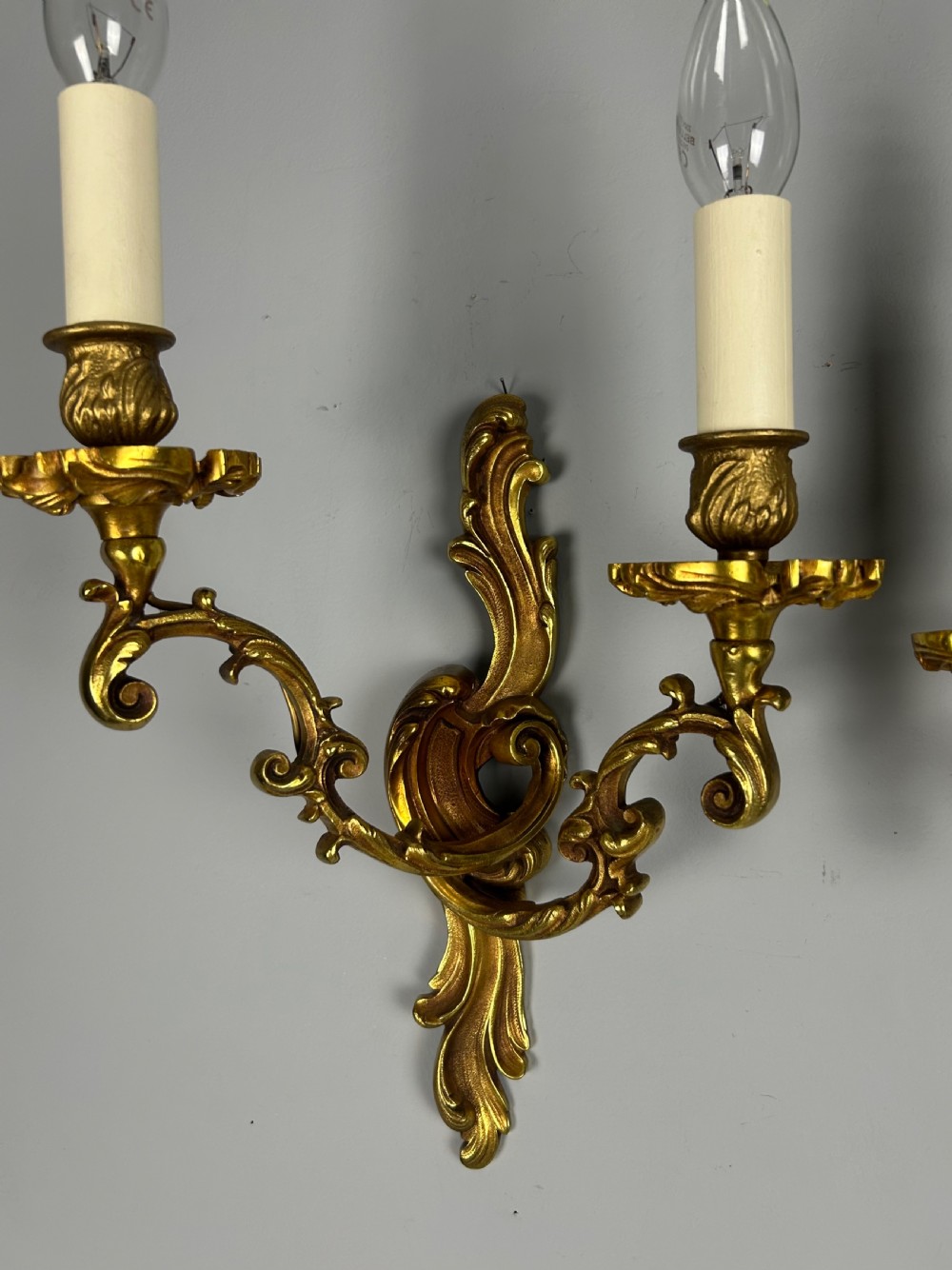 A pair of French Rococo style gilded bronze two-arm wall sconces decorated with ornate acanthus leaf scrollwork. View VI
