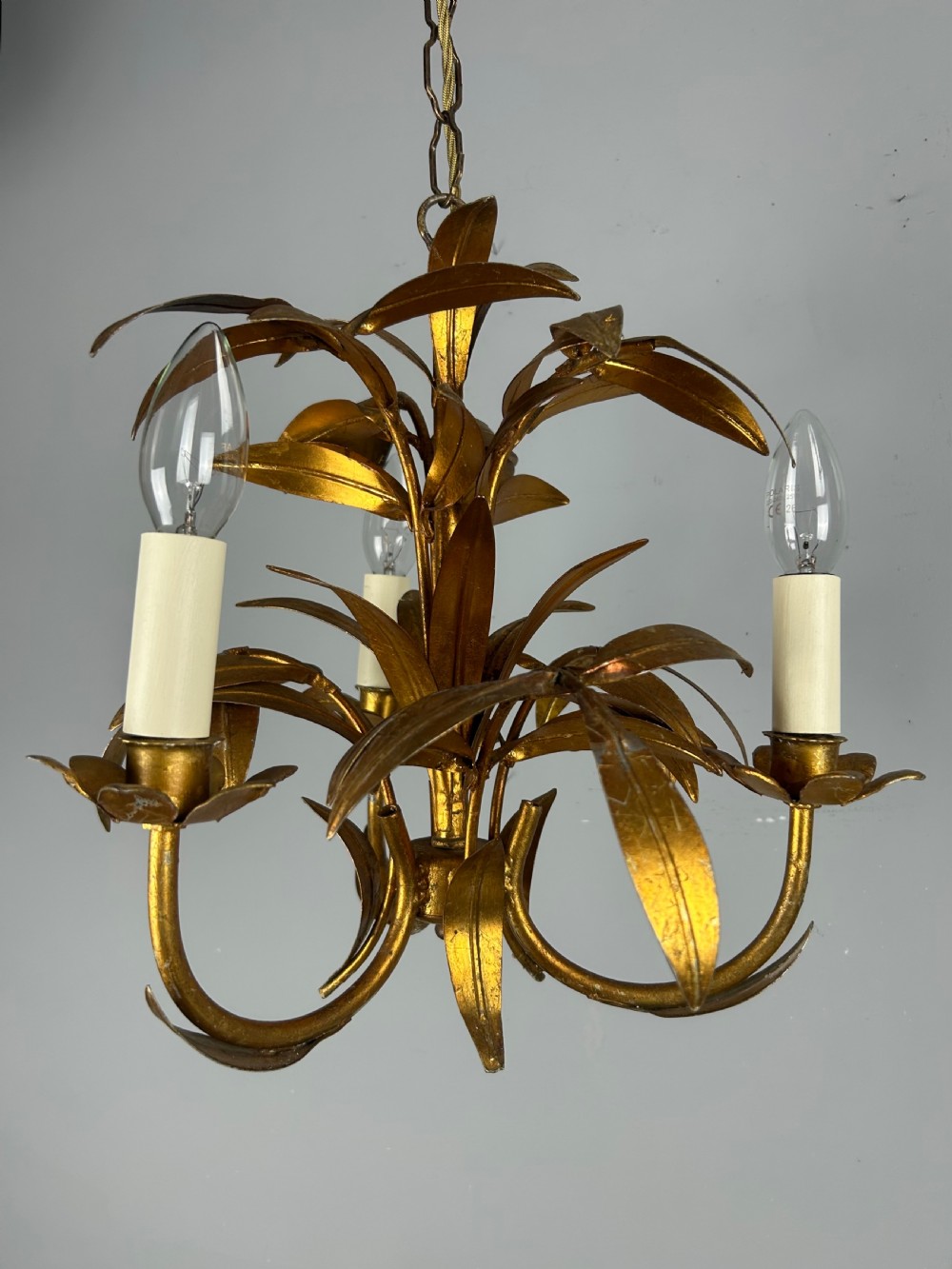 A French gilt metal three-light chandelier featuring curved arms and hand-shaped botanical leaf decoration.