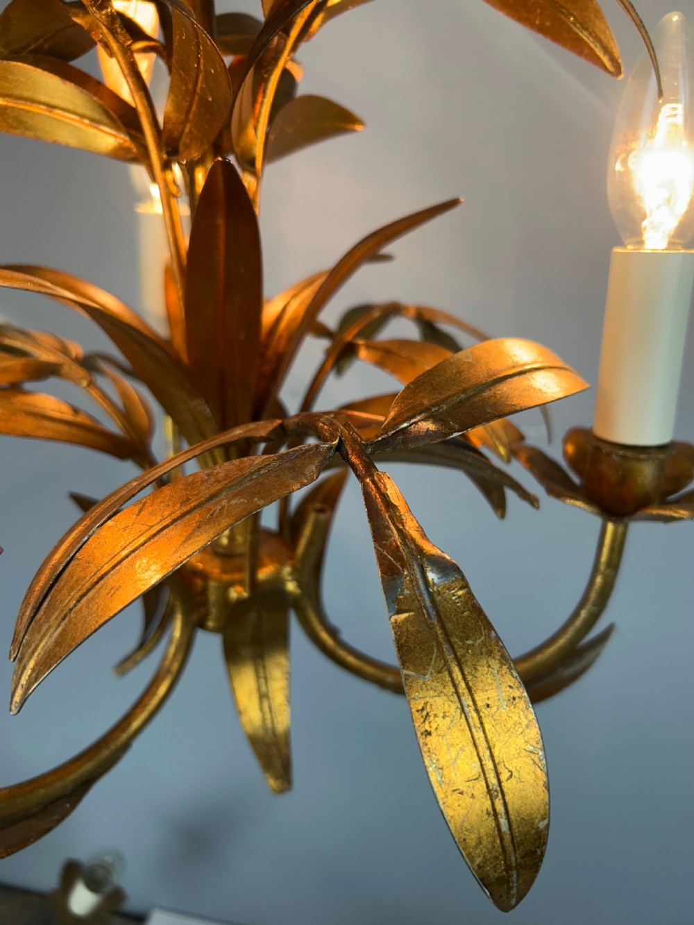 A French gilt metal three-light chandelier featuring curved arms and hand-shaped botanical leaf decoration. View III