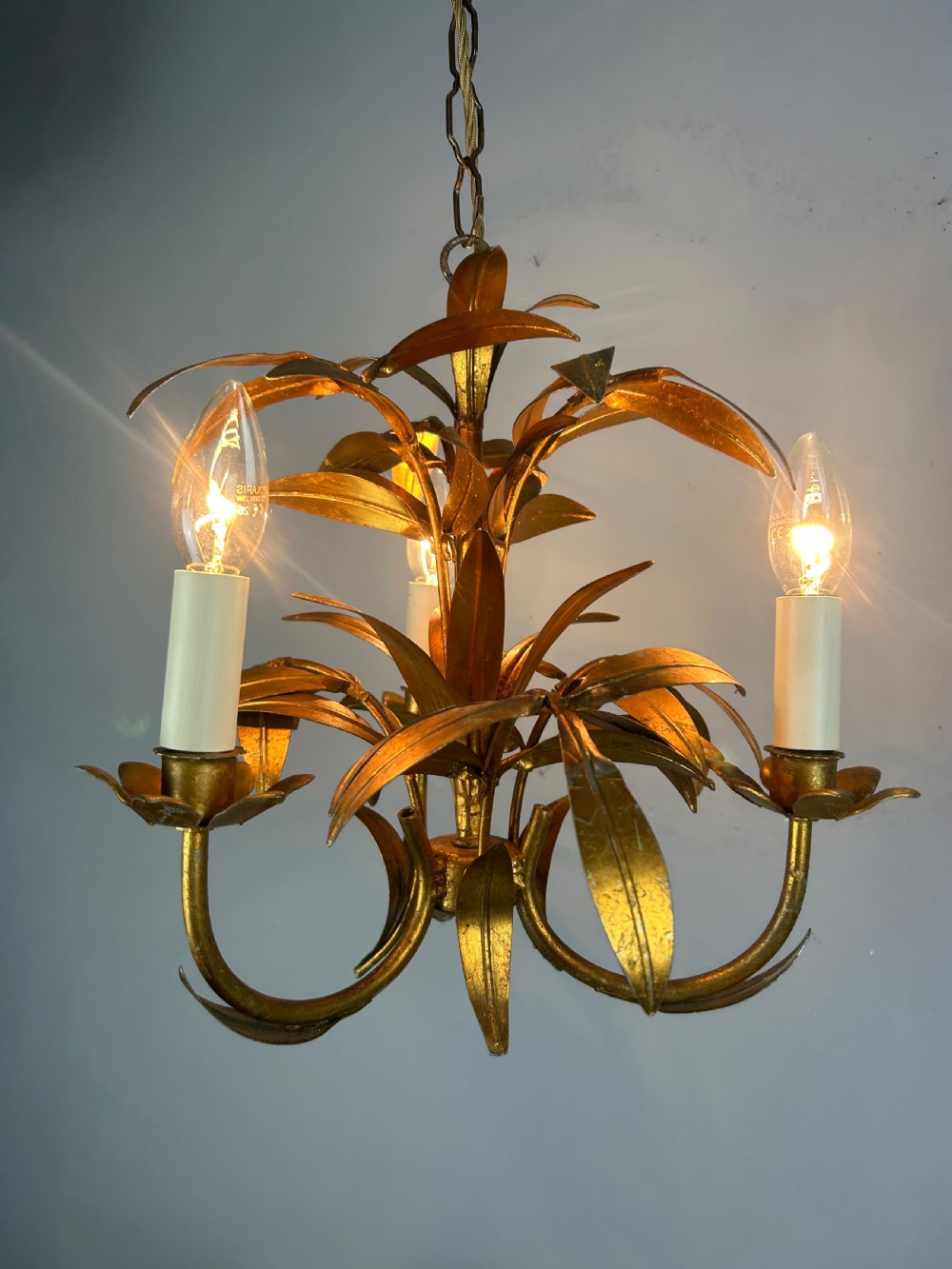 A French gilt metal three-light chandelier featuring curved arms and hand-shaped botanical leaf decoration. View V