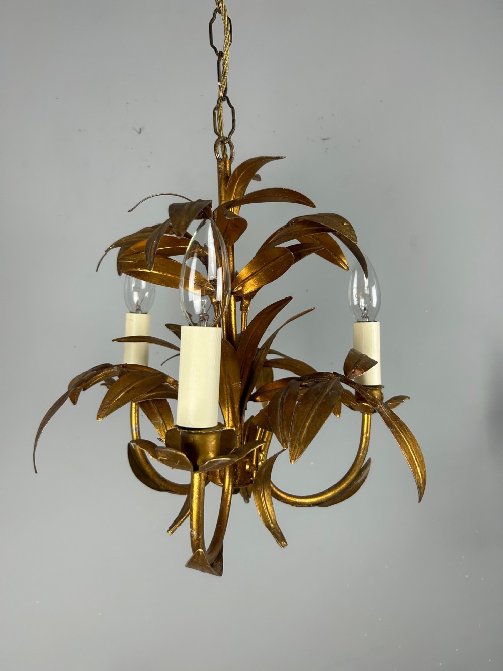 A French gilt metal three-light chandelier featuring curved arms and hand-shaped botanical leaf decoration. View VII