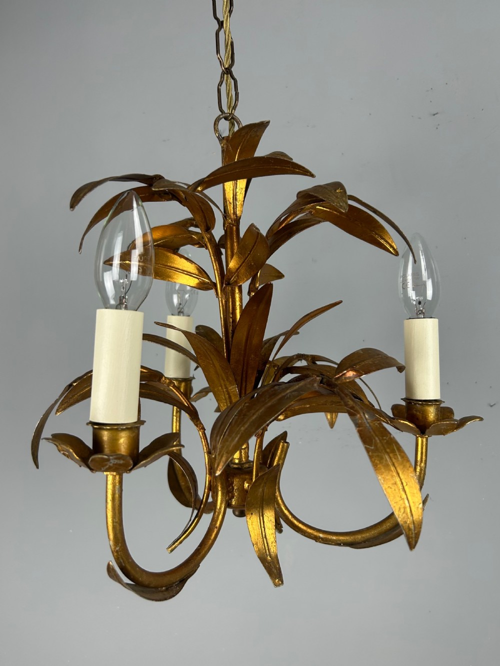A French gilt metal three-light chandelier featuring curved arms and hand-shaped botanical leaf decoration. View XII