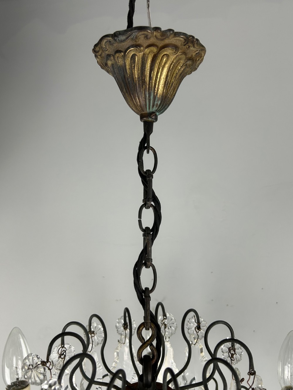 An antique French six-light chandelier crafted from dark patinated brass scrollwork and adorned with faceted glass crystal drops and candle-effect fittings. View XII