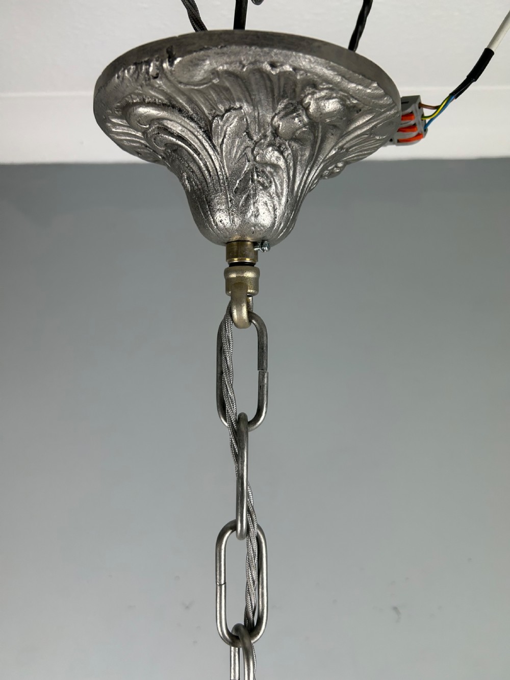 An antique silver-plated six-light chandelier featuring curved scrolling arms, gadrooned drip pans, cream candle sleeves, and a central baluster stem. View XVIII