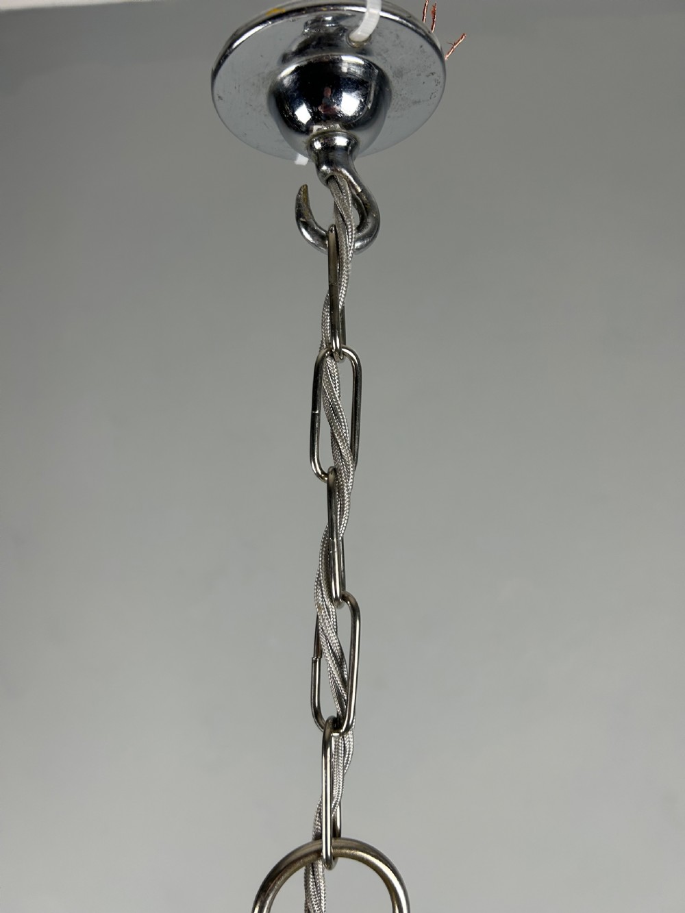 A clear cut glass acorn-shaped shade topped with a scrollwork chrome crown gallery and suspended wire. View V