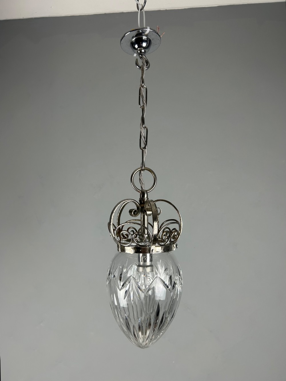 A clear cut glass acorn-shaped shade topped with a scrollwork chrome crown gallery and suspended wire. View VI