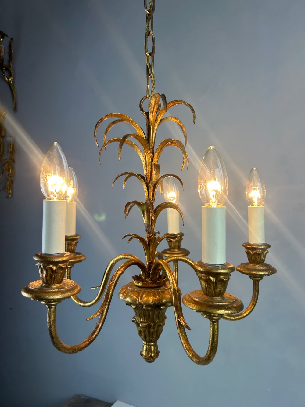 A five-light French gilt metal chandelier featuring curved branches, central leaf foliage design, and cream candle sleeves. View II