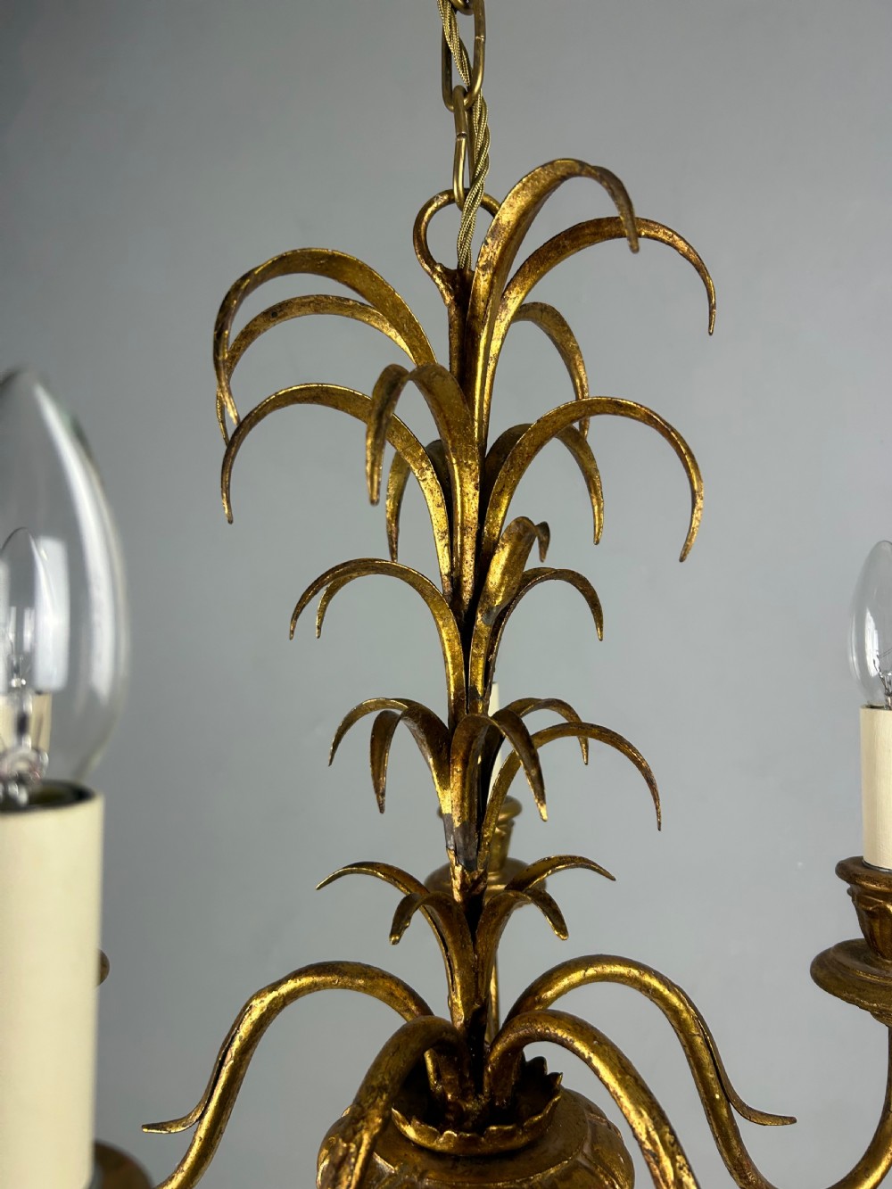 A five-light French gilt metal chandelier featuring curved branches, central leaf foliage design, and cream candle sleeves. View V