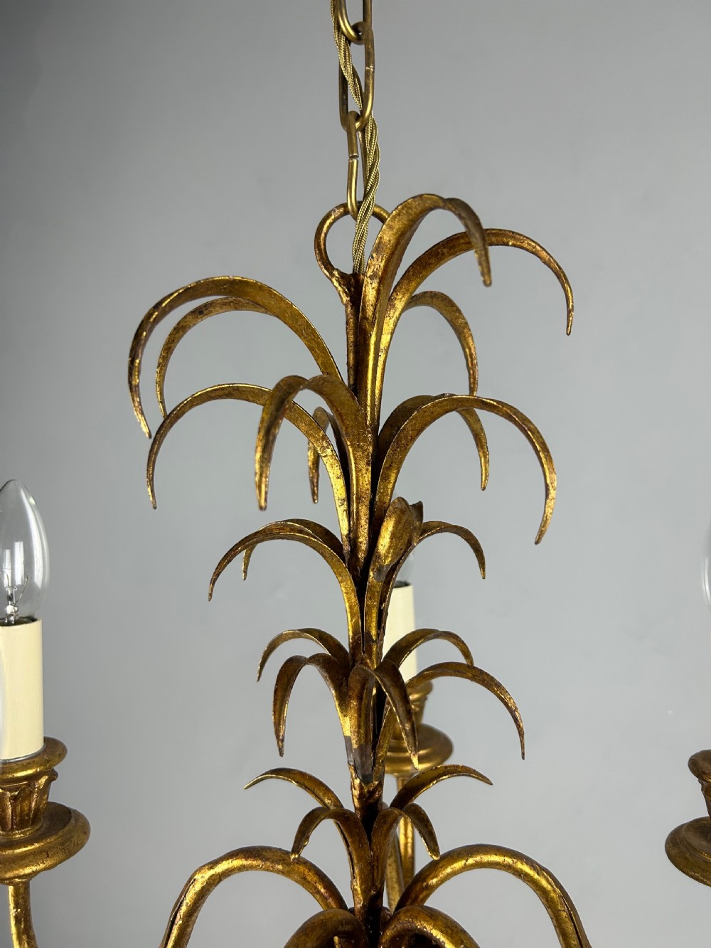 A five-light French gilt metal chandelier featuring curved branches, central leaf foliage design, and cream candle sleeves. View VII