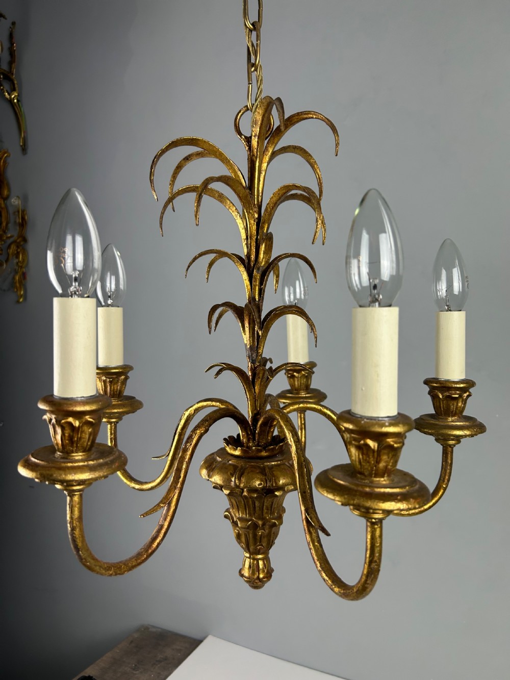 A five-light French gilt metal chandelier featuring curved branches, central leaf foliage design, and cream candle sleeves. View IX